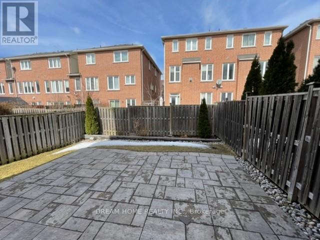 A brick apartment building with a fenced in backyard.