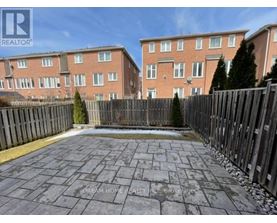 A brick apartment building with a fenced in backyard.