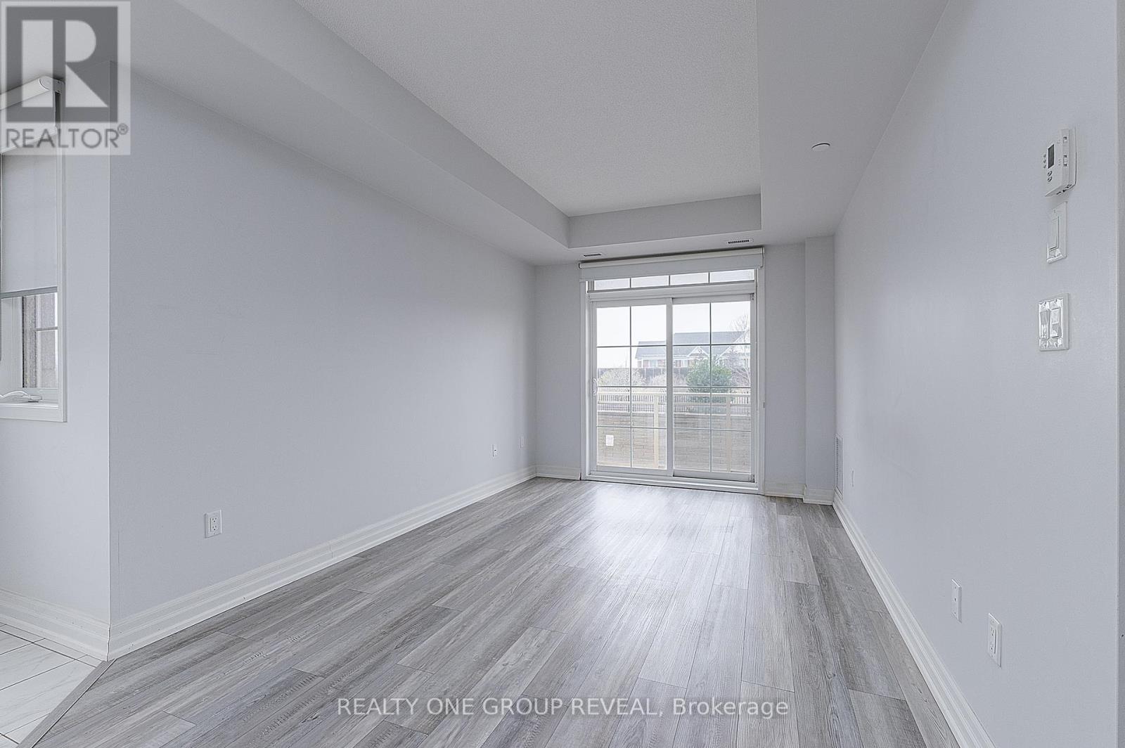 A spacious room with a window and wooden flooring.