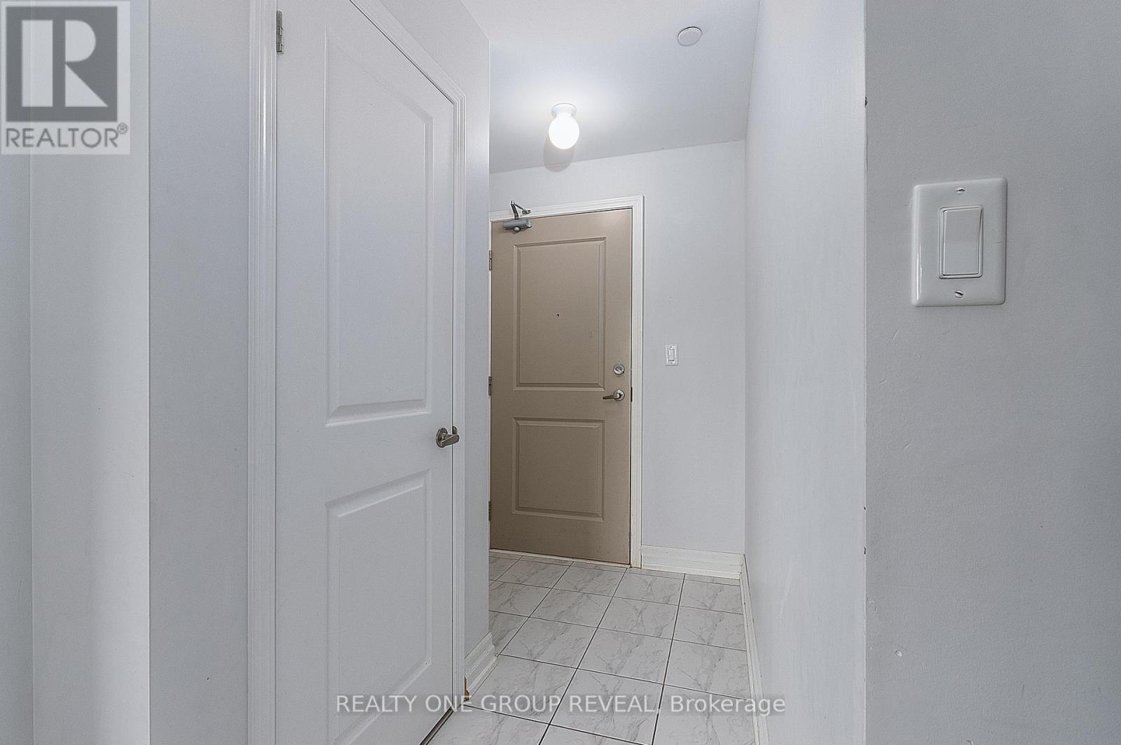A hallway with a white door on the left and a beige door on the right.