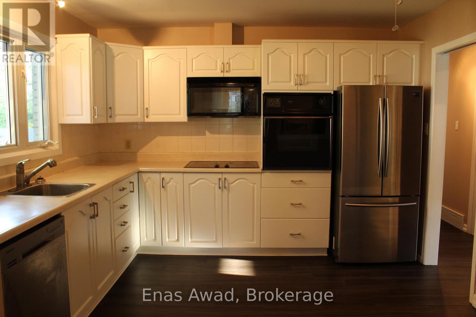 A kitchen with white cabinets and a stainless steel refrigerator.