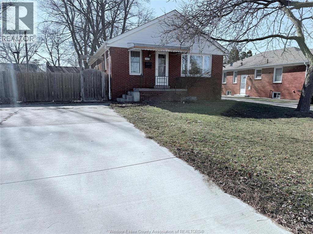 A red brick house with a white door and a white fence.