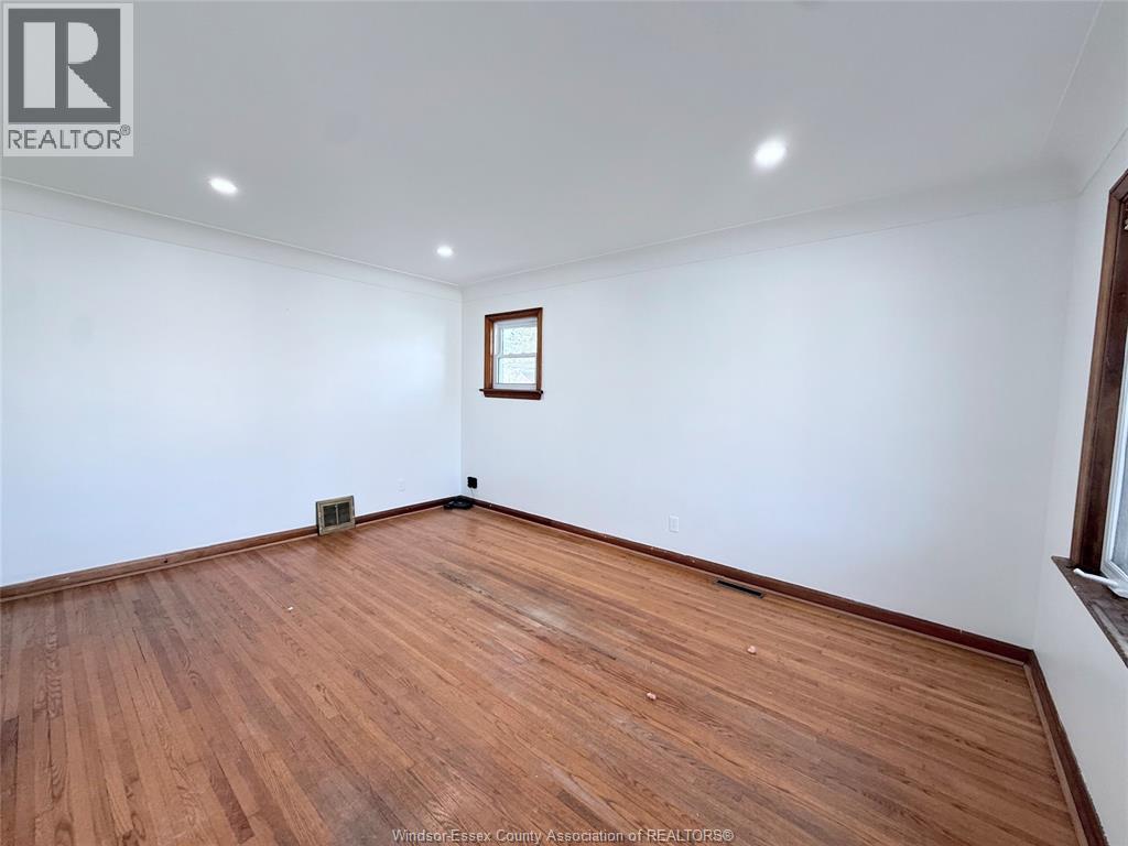 A room with wooden flooring and a picture frame on the wall.