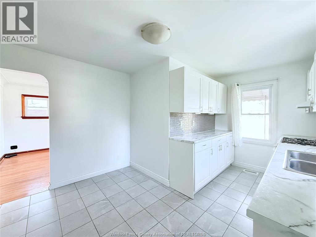 A kitchen with white cabinets and a marble countertop.