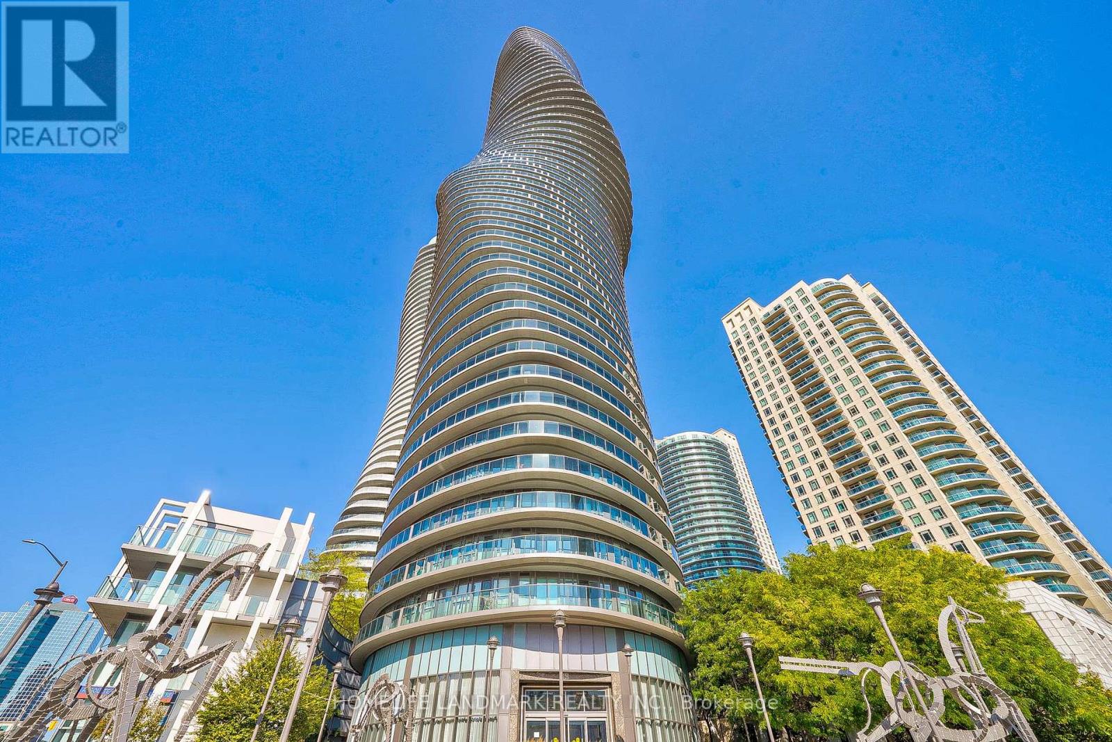 A tall building with a curved top stands out against a clear blue sky.