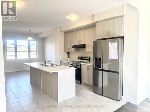 A kitchen with white cabinets and a black fridge.