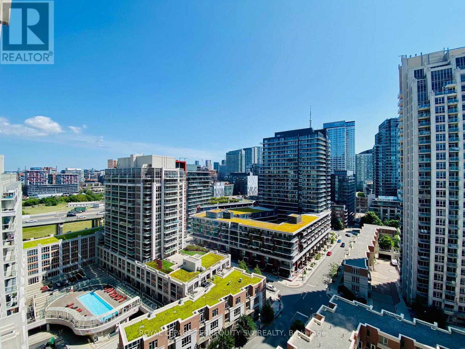 A cityscape with a swimming pool in the foreground and a clear blue sky above.