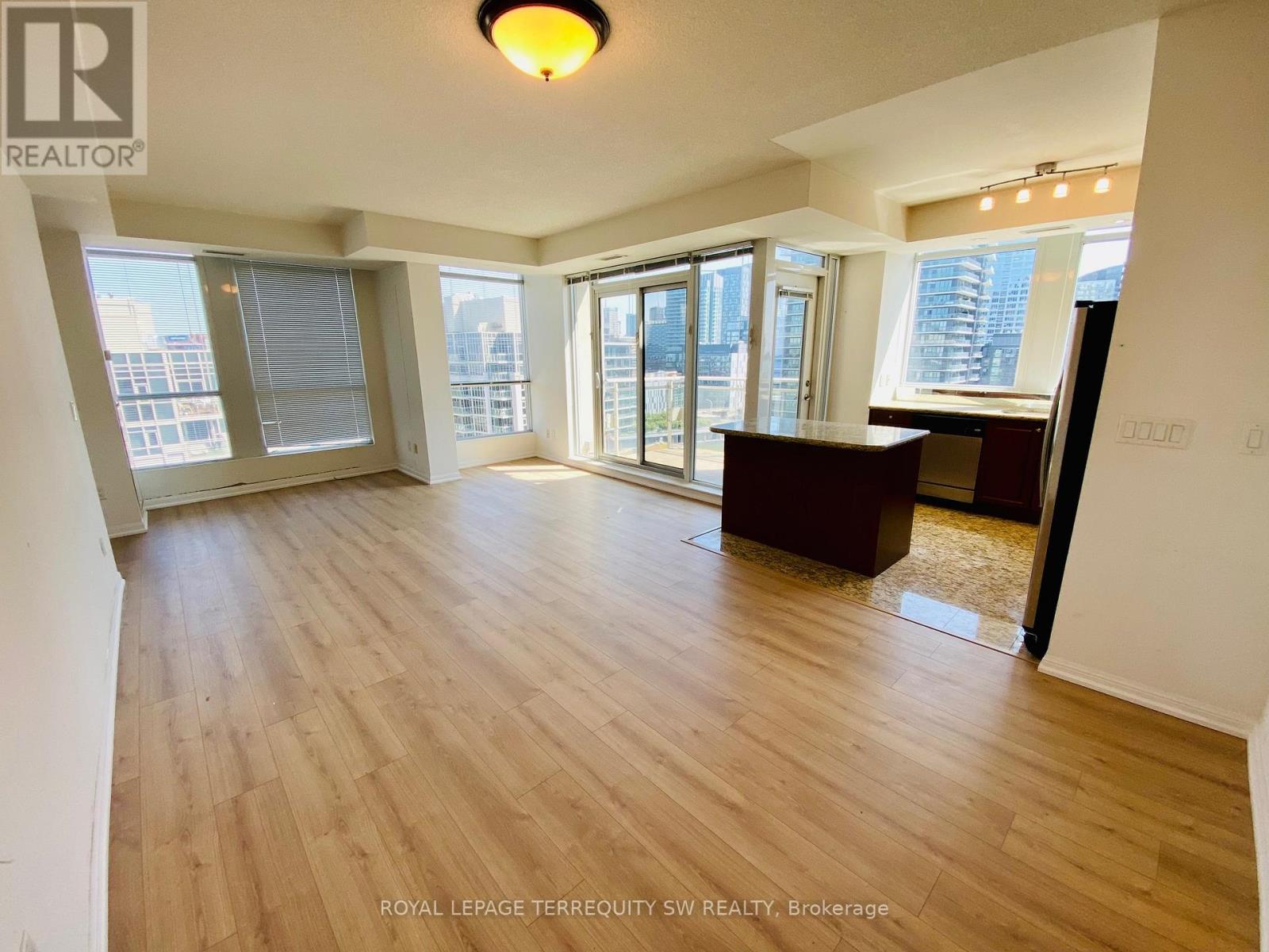 A spacious room with wooden flooring and large windows.