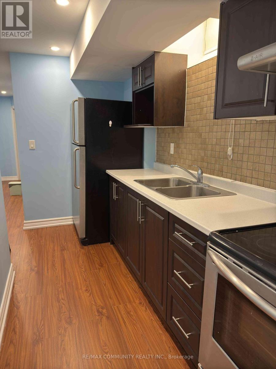 A kitchen with a black fridge and wooden floors.