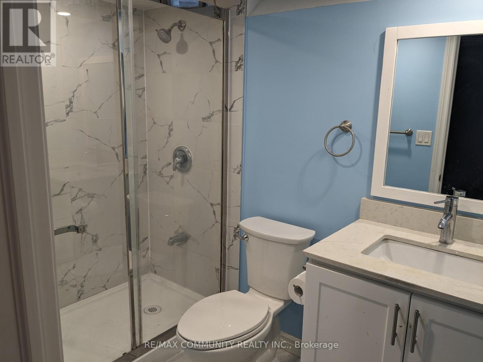 A bathroom with a toilet, sink, and shower with a marble floor.