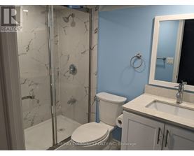 A bathroom with a toilet, sink, and shower with a marble floor.