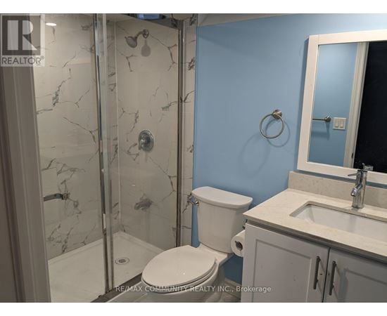 A bathroom with a toilet, sink, and shower with a marble floor.