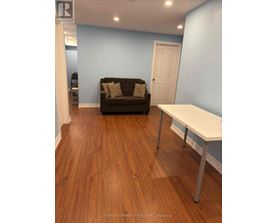 A brown couch sits in a room with a white table.