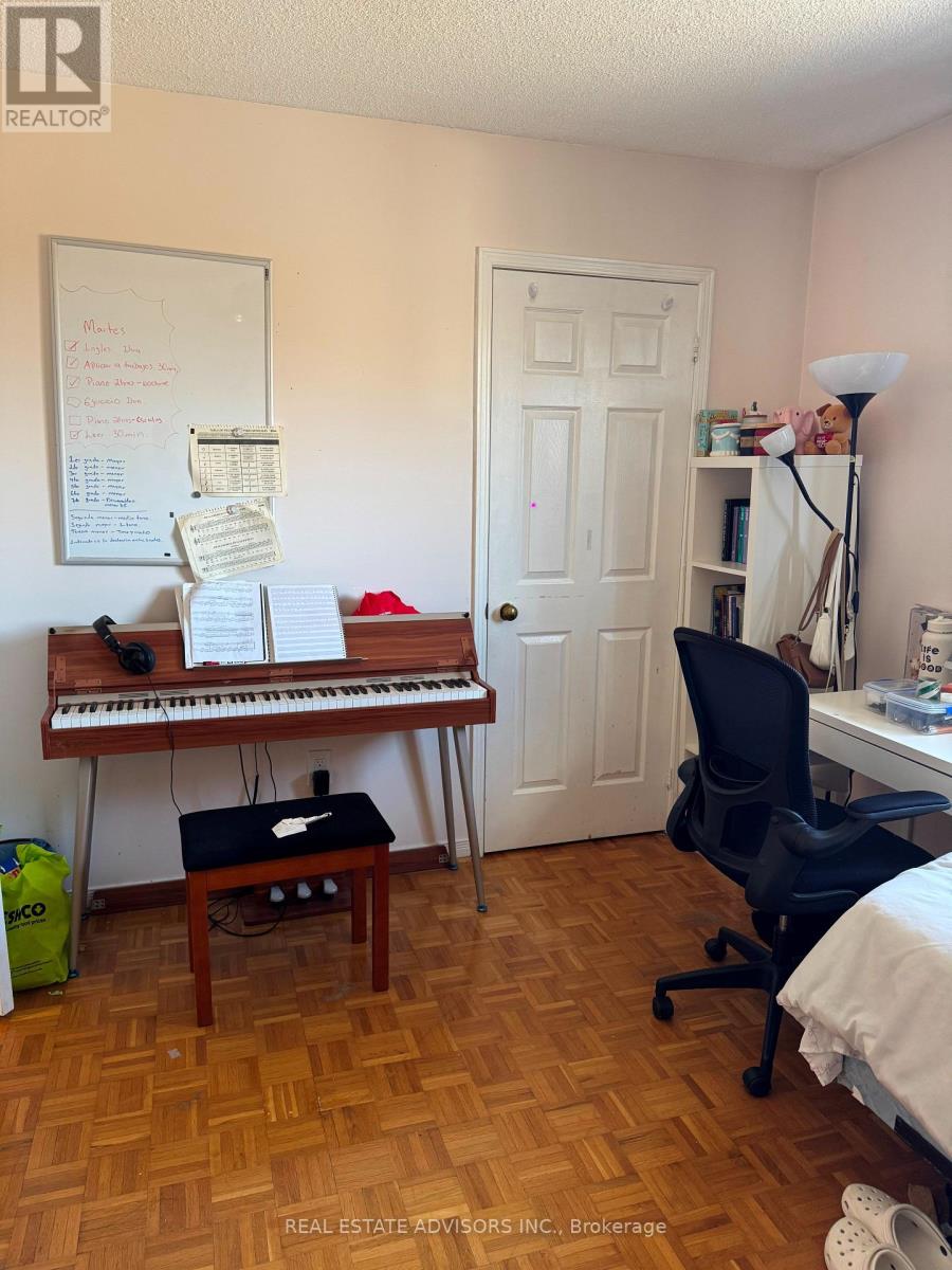 A room with a piano, a chair, and a whiteboard with writing on it.