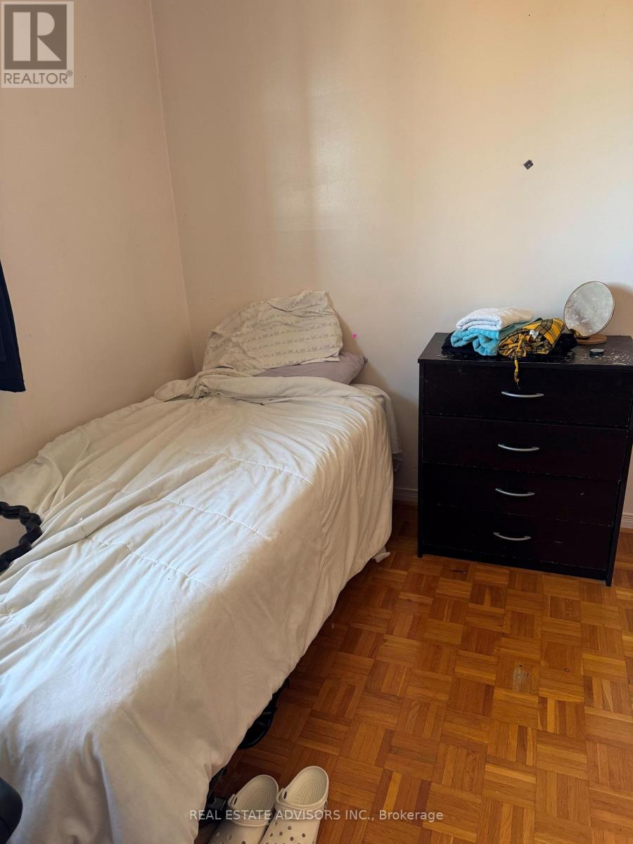 A bedroom with a bed, nightstand, and wooden flooring.