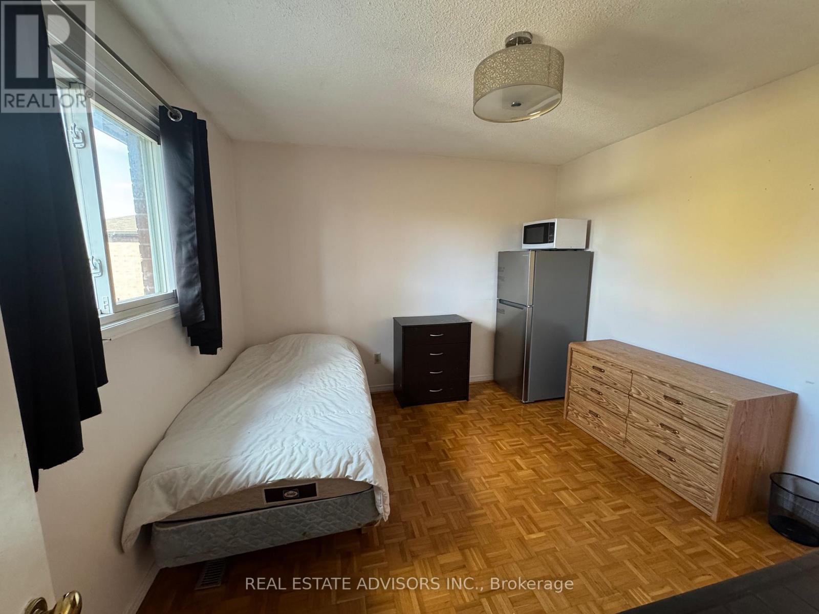 A bedroom with a bed, desk, chair, and window.