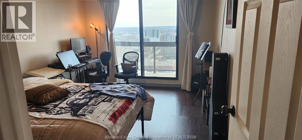 A bedroom with a large bed and a balcony with a view of the city.