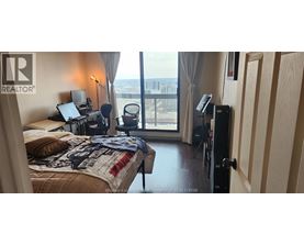 A bedroom with a large bed and a balcony with a view of the city.