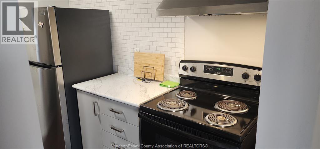A kitchen with a black fridge and a black stove top oven.