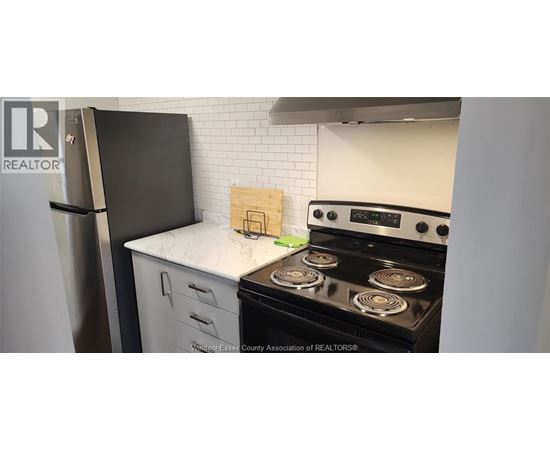 A kitchen with a black fridge and a black stove top oven.