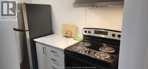 A kitchen with a black fridge and a black stove top oven.