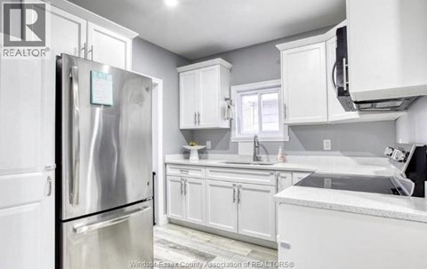 A kitchen with white cabinets and a stainless steel refrigerator.
