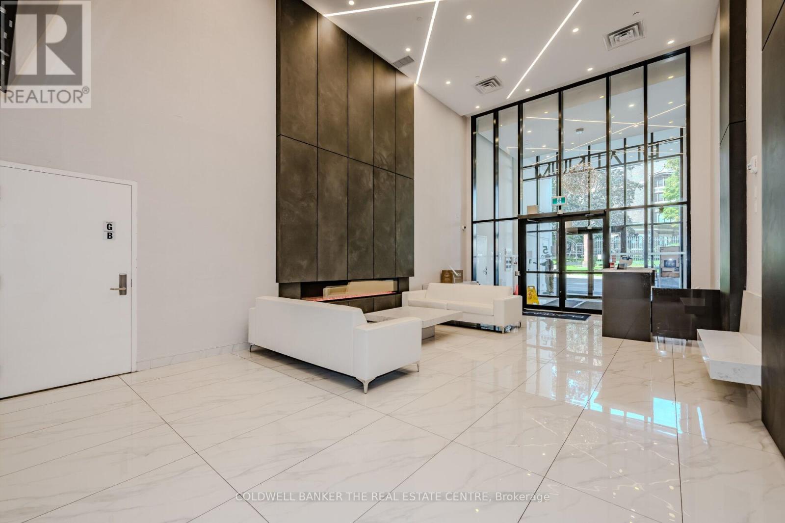A spacious lobby with a white reception desk and a large window.