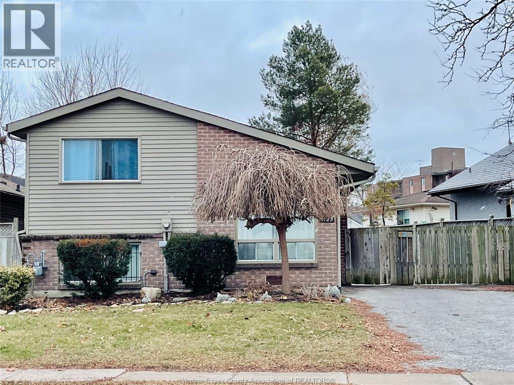 A house with a grey roof and a tree in front of it.