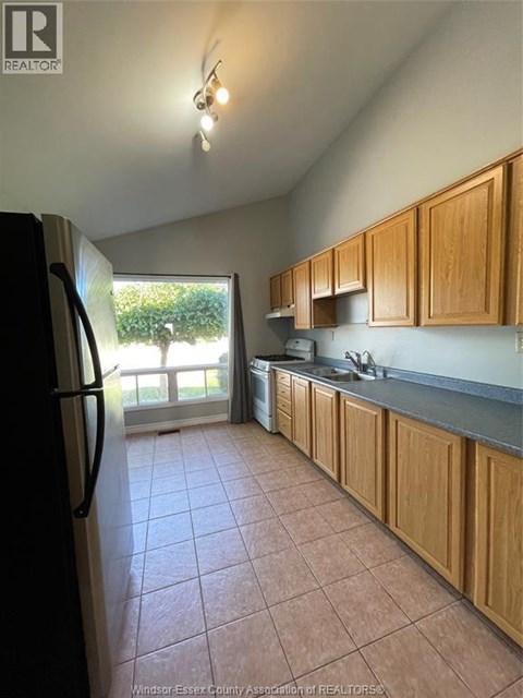 A kitchen with wooden cabinets and a black fridge.