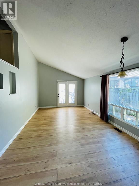 A room with wooden flooring and a window with blinds.