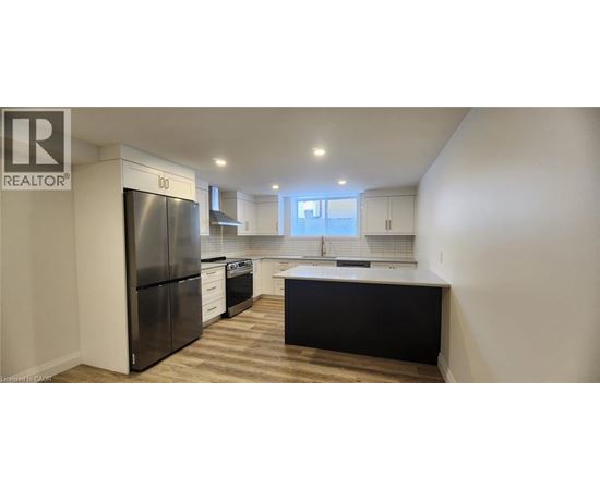 A kitchen with a black refrigerator and wooden floors.