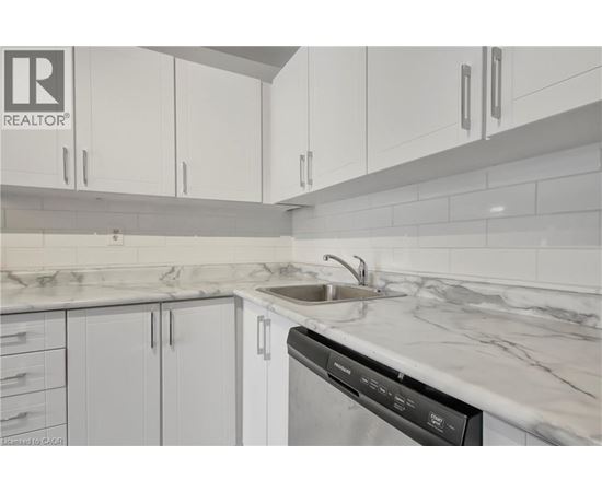 A modern kitchen with white cabinets and a marble countertop.