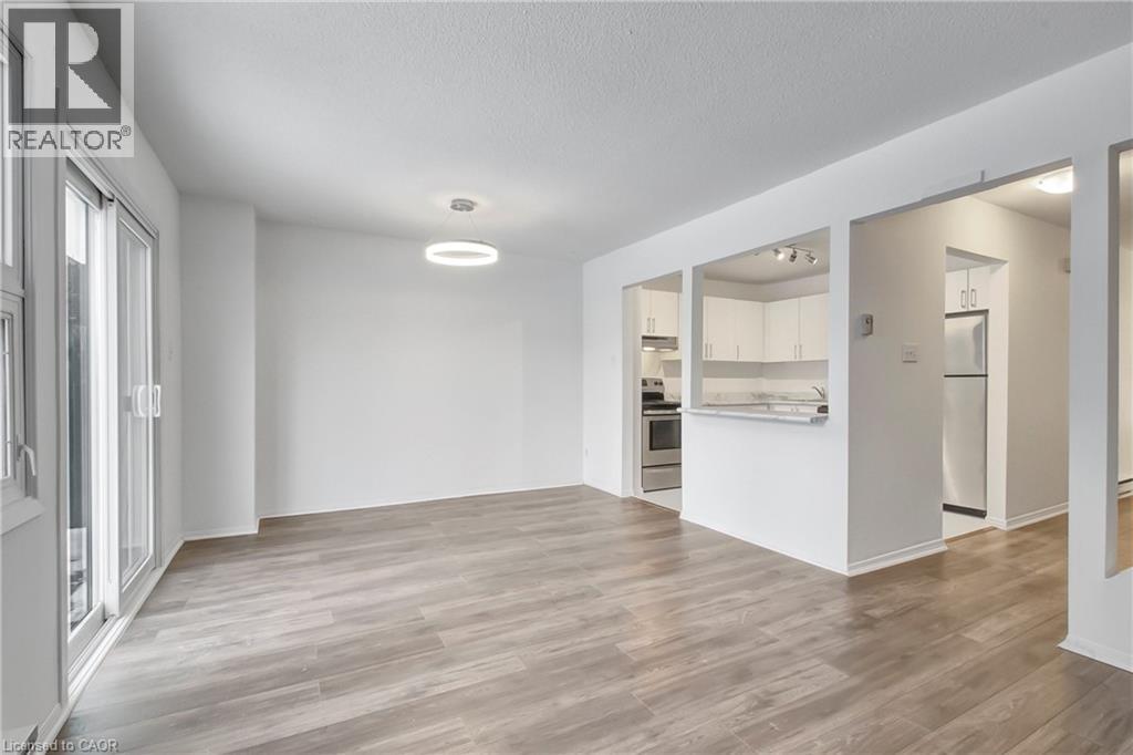 A spacious room with wooden flooring and white walls, with a doorway leading to another room.
