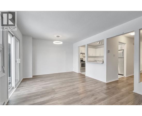A spacious room with wooden flooring and white walls, with a doorway leading to another room.