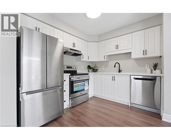 A modern kitchen with a stainless steel refrigerator and white cabinets.
