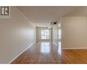 A spacious room with wood flooring and a large window.