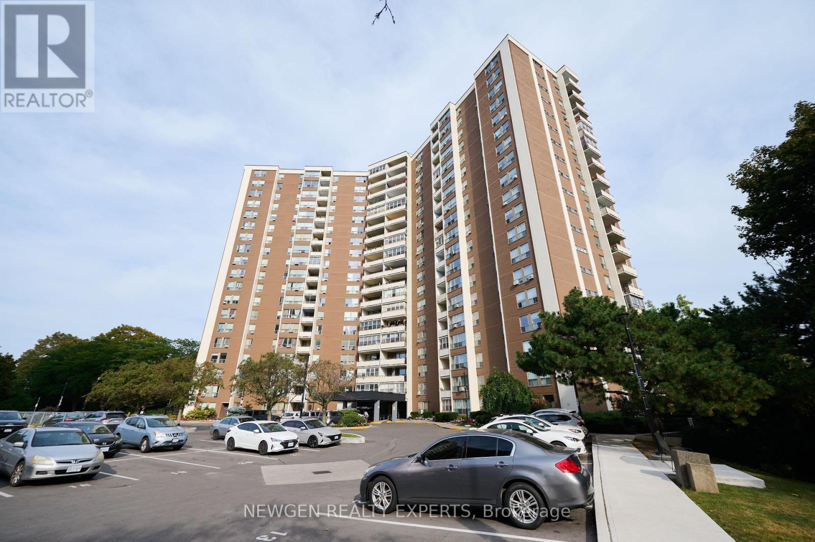 A tall apartment building with a parking lot in front of it.