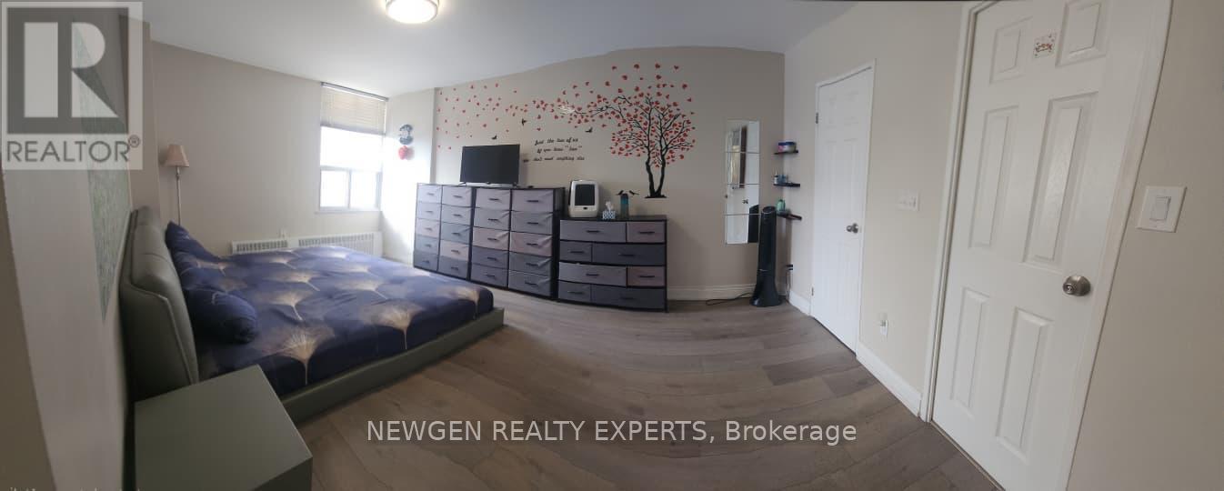 A bedroom with a bed, dresser, and a wall with a tree design.