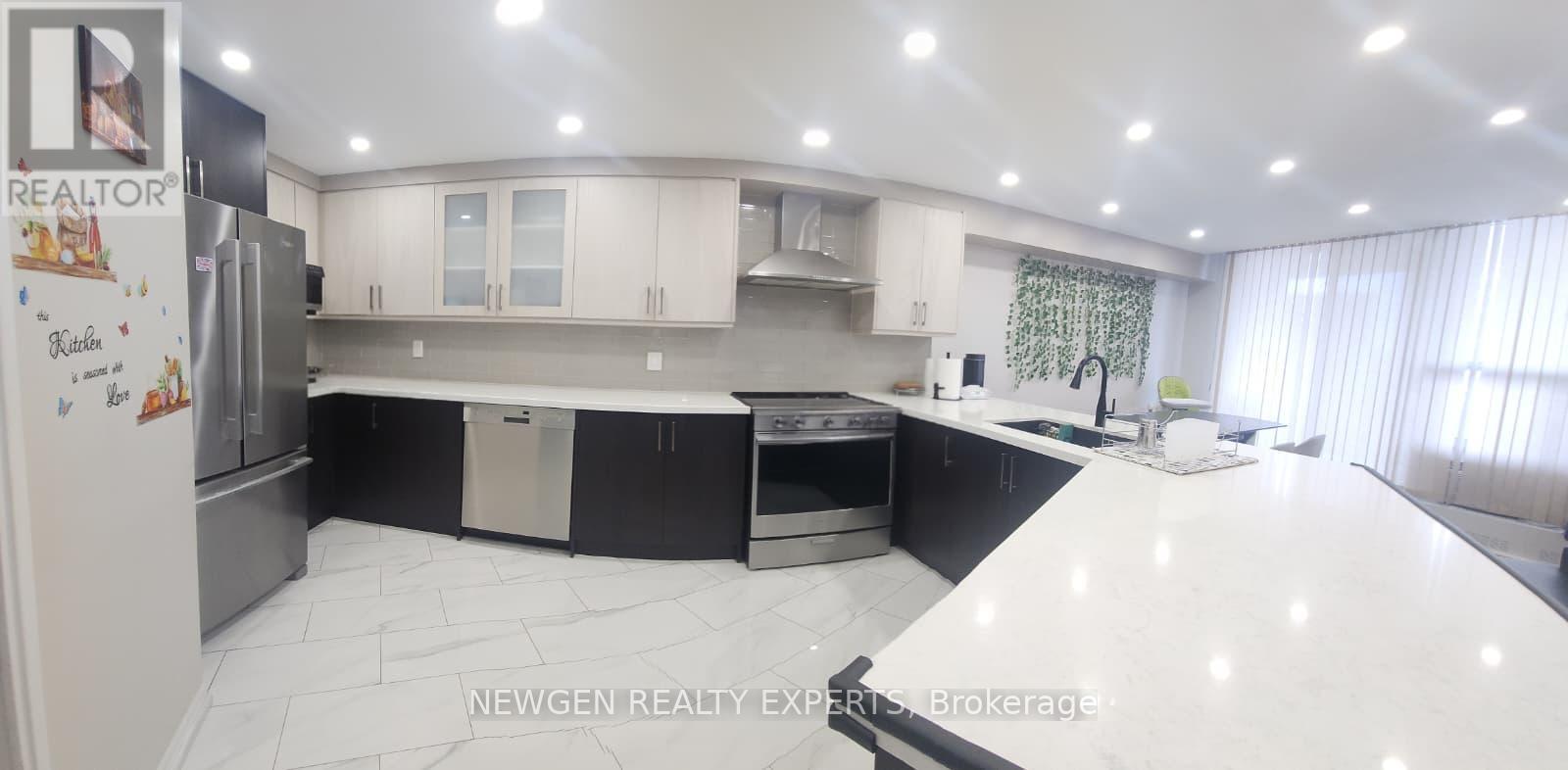 A spacious kitchen with black and white cabinets and a refrigerator.
