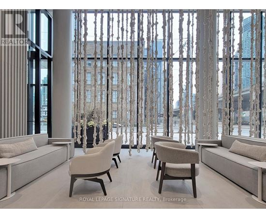 A living room with white furniture and a view of a city skyline through a window.