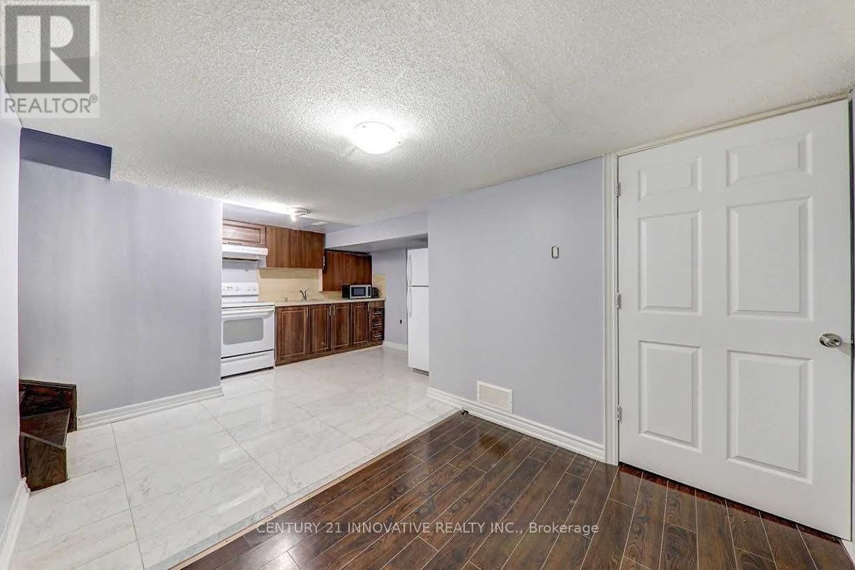 A spacious room with a white door and a kitchen area in the background.