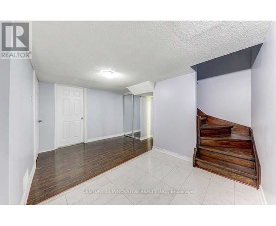 A room with a white ceiling, wooden floor, and a wooden bench.