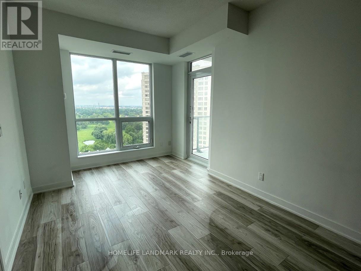 A room with wooden flooring and a large window overlooking a cityscape.