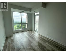 A room with wooden flooring and a large window overlooking a cityscape.