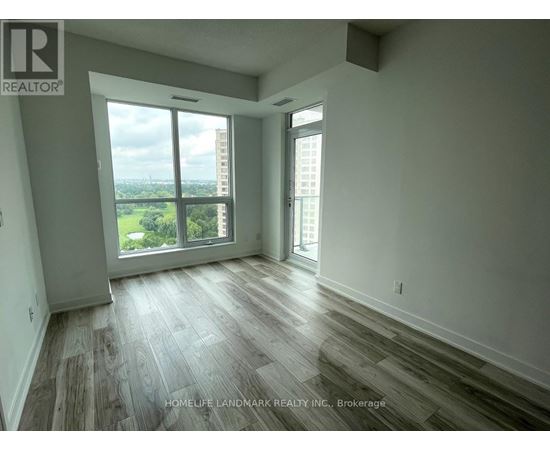 A room with wooden flooring and a large window overlooking a cityscape.
