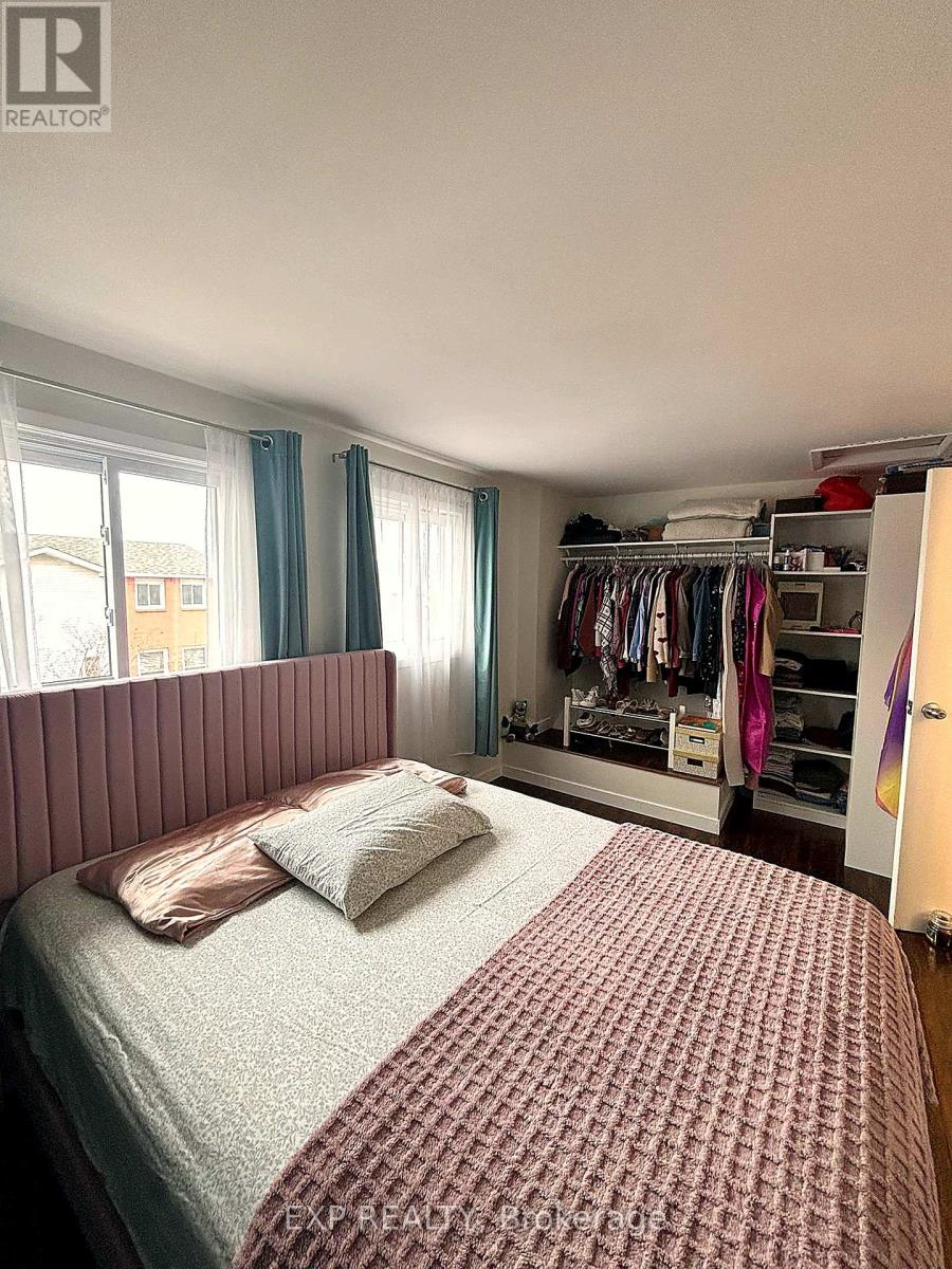 A bedroom with a bed, a window with blue curtains, and a wardrobe with clothes.
