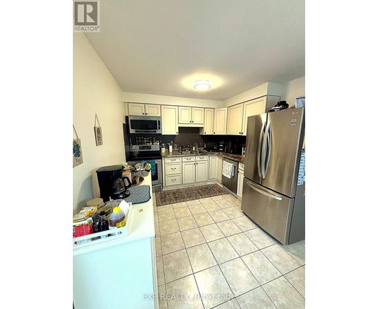 A kitchen with a refrigerator, microwave, and oven.