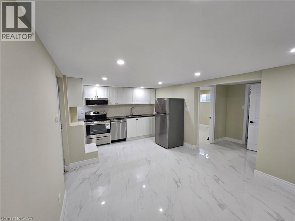 A spacious kitchen with white marble flooring and modern appliances.