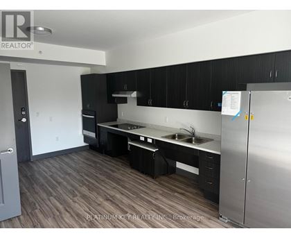 A kitchen with black cabinets and a stainless steel refrigerator.
