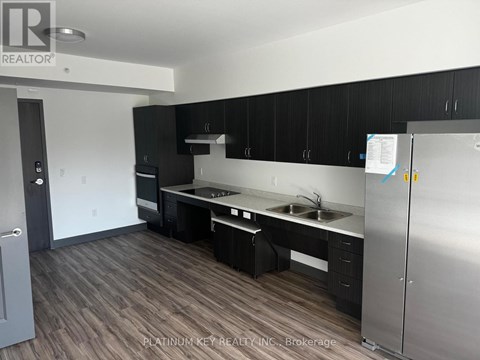 A kitchen with black cabinets and a stainless steel refrigerator.